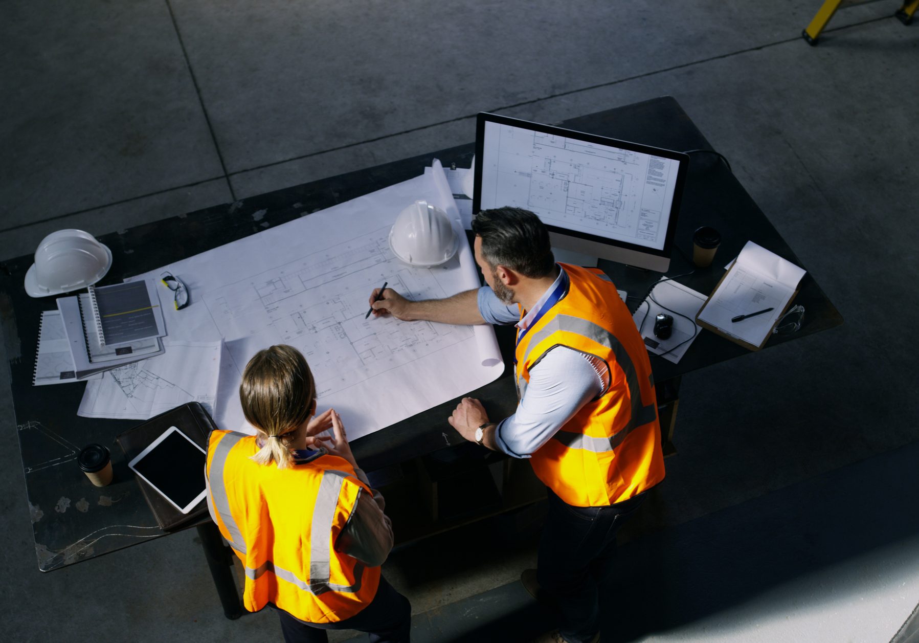 High angle shot of two engineers going over a blueprint together in an industrial place of work