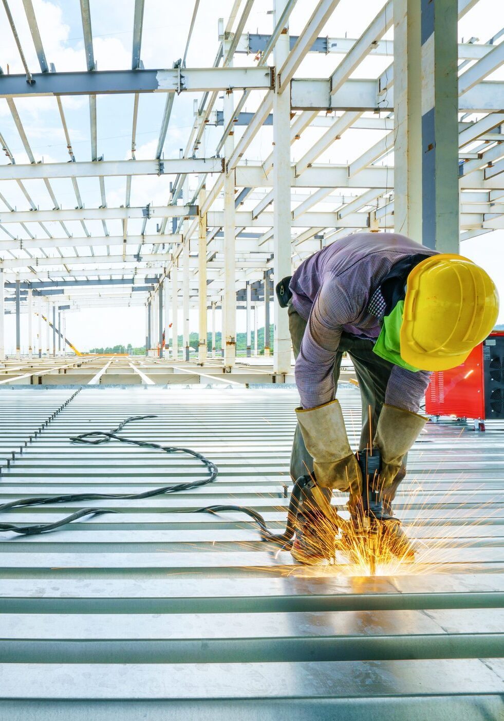 Welder are welds re-bar shear keys metal deck slab of mezzanine floor under the construction building in the factory with blue sky