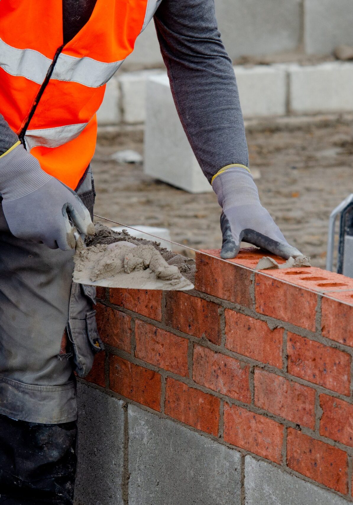 Bricklayer laying bricks on mortar on new residential house construction