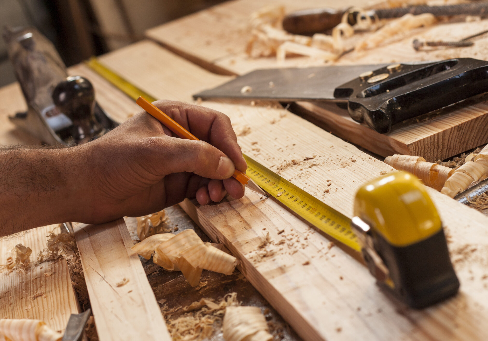 carpenter taking measurement of a wooden plank